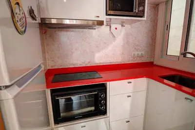 a small kitchen with white cabinets and a microwave at Aquarium Apartment by Hello Homes Sitges in Sitges