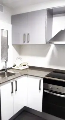 a kitchen with white cabinets and a sink at Apartamentos Atlas Terrassa III in Terrassa