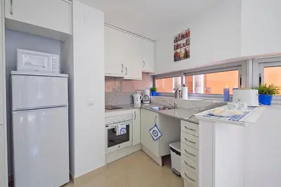 a kitchen with white cabinets and a white refrigerator at Charmsuites Paralel in Barcelona