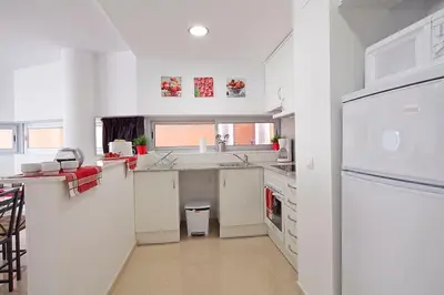 a white kitchen with a sink and a refrigerator at Charmsuites Paralel in Barcelona