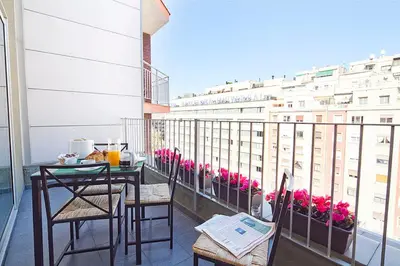 a balcony with a table and chairs and a building at Charmsuites Paralel in Barcelona