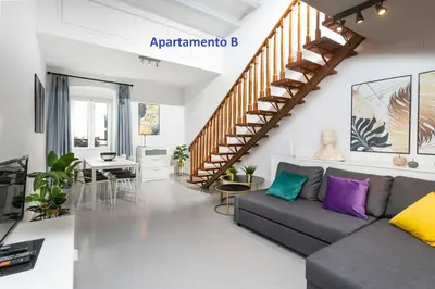 a living room with a couch and a staircase at Sitges Rustic Apartments in Sitges