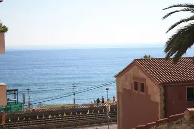 a view of the ocean with people walking on the tracks at Apartament Cal Negre in Vilassar de Mar