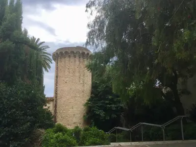 a tall brick building with a tower next to trees at Apartament Cal Negre in Vilassar de Mar