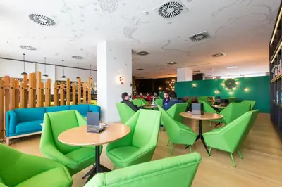 a restaurant with green chairs and tables and people at Vincci Bit in Barcelona
