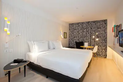 a hotel room with a large white bed and a desk at Vincci Bit in Barcelona