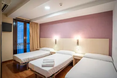a hospital room with three beds and a window at Hostal Fina in Barcelona