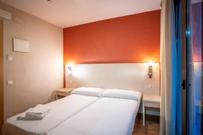 a bedroom with two white beds and a red wall at Hostal Fina in Barcelona