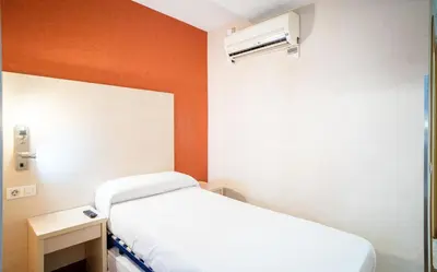 a hospital room with a bed and a air conditioner at Hostal Fina in Barcelona