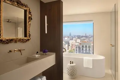 a bathroom with a tub and a sink and a mirror at The Barcelona EDITION in Barcelona