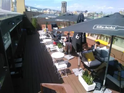a row of chairs and tables on a rooftop patio at Kabul Party Hostel Barcelona in Barcelona