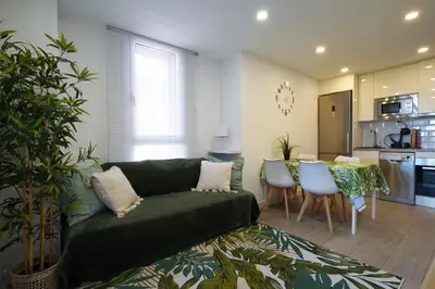 a living room with a green couch and a kitchen at Calm, Beach and Bikes in Castelldefels