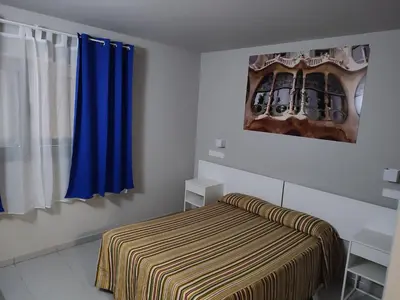 a bedroom with a bed and a blue curtain at Hotel Blauet by Bossh! Hotels in El Prat de Llobregat