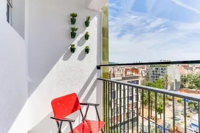 a red chair on a balcony with a view of the city at Sweett - Eixample Borrell in Barcelona