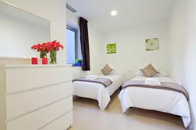 two beds in a room with white walls and flowers at Charmsuites Nou Rambla in Barcelona