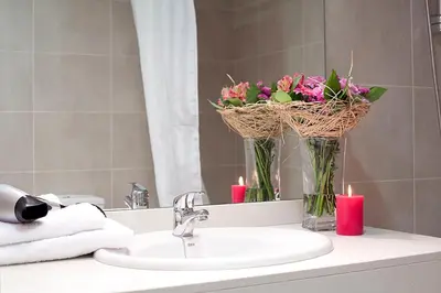 a bathroom sink with two candles and flowers in a mirror at Charmsuites Nou Rambla in Barcelona