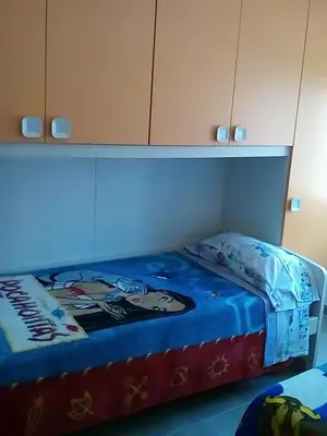 a bed with a blue blanket on top of it at Piso luminoso en Barcelona in Barcelona