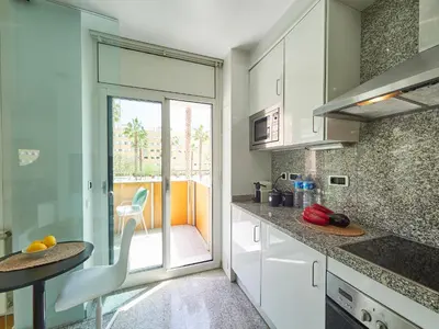 a kitchen with white cabinets and a table and a window at BarcelonaForRent Vila Olimpica Pool Suites in Barcelona