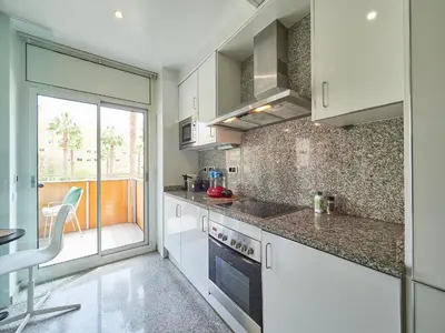 a kitchen with white cabinets and a table and a chair at BarcelonaForRent Vila Olimpica Pool Suites in Barcelona