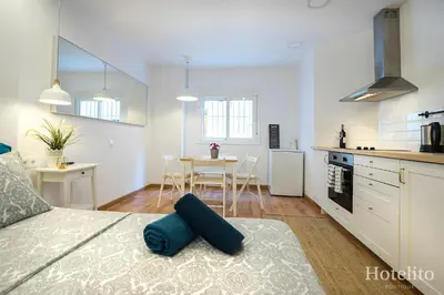a bedroom with a bed and a kitchen with a table at Hotelito Boutique Cinca in Hospitalet de Llobregat