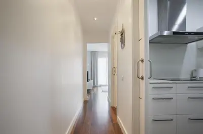 a kitchen with white cabinets and a wooden floor at Tendency Rambla del Poblenou in Barcelona