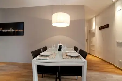 a white dining room table with chairs and a light fixture at Serennia Apartamentos Ramblas - Plaça Catalunya in Barcelona