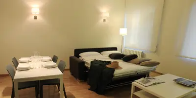 a living room with a bed and a table and a table and chairs at Alguera Apartments Napols in Barcelona