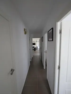 a hallway with white walls and a tile floor at Apartamento Maraka Playa Castelldefels in Castelldefels