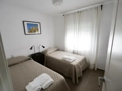 a hotel room with two beds and a window at Apartamento Maraka Playa Castelldefels in Castelldefels