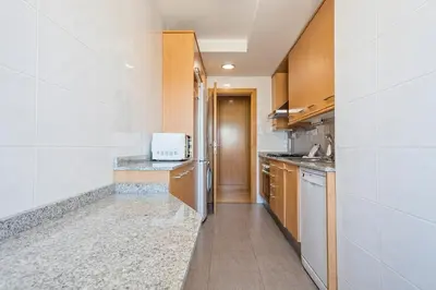 a kitchen with wooden cabinets and a sink at Alcam Badalona Playa Norte in Badalona