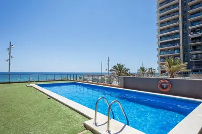 a swimming pool with the ocean in the background at Alcam Badalona Playa Norte in Badalona