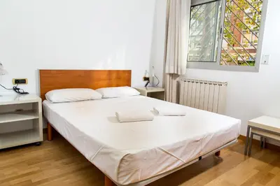 a bedroom with a white bed with a wooden headboard and a window at Apartamentos City Beach in Barcelona