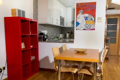 a kitchen with a wooden table and a red cabinet at Apartamentos City Beach in Barcelona
