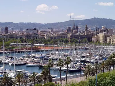 a group of boats docked in a harbor with a city at Barceloneta Port Ramblas in Barcelona