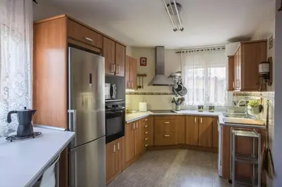 a kitchen with wooden cabinets and a stainless steel refrigerator at Amazing Vila close to Sitges, jacuzzi, swimming pool & exellent views in Olivella