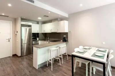 a kitchen with a table and chairs and a refrigerator at Espais Blaus Apartments in Barcelona