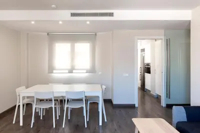 a white dining room with a white table and chairs at Espais Blaus Apartments in Barcelona