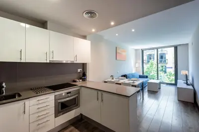 a kitchen with white cabinets and a dining room at Espais Blaus Apartments in Barcelona