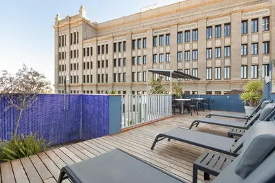 a deck with chairs and tables in front of a building at Enjoybcn Dali Apartments in Barcelona