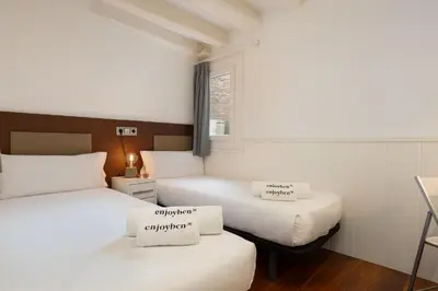 two beds in a small room with white sheets at Enjoybcn Dali Apartments in Barcelona