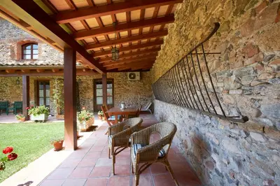 a patio with chairs and a table and a stone wall at Mas Can Calet Aparthotel in Les Franqueses del Vallès