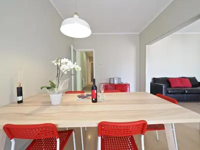 a dining room table with red chairs and a bottle of wine at Sagrada Penthouse in Barcelona