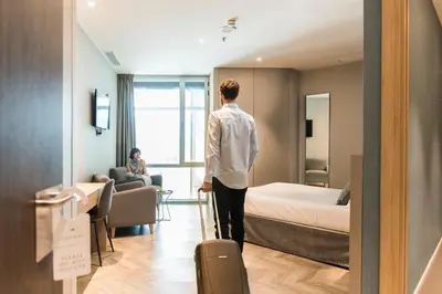 a man standing in a hotel room with a suitcase at Sleep&Fly in El Prat de Llobregat