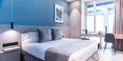 a bedroom with a large bed with a blue wall at Sleep&Fly in El Prat de Llobregat