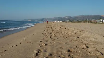 a beach with a person walking on the sand at VILLA BELLA ESTANÇA in Castelldefels