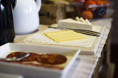 a table with a box of cheese and a plate of food at Anita's Bed and Breakfast in Barcelona