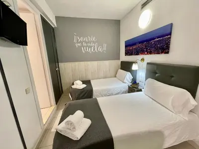 a hotel room with two beds and a tv at Hostal Lleida in Barcelona