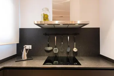 a kitchen with a black counter top with utensils at Petit Luxe l'Àtic in Terrassa