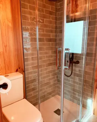 a bathroom with a toilet and a glass shower at HolaCamp Sitges Garrofer in Sitges