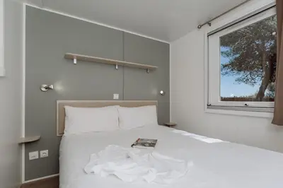 a bedroom with a large white bed with a window at HolaCamp Sitges Garrofer in Sitges